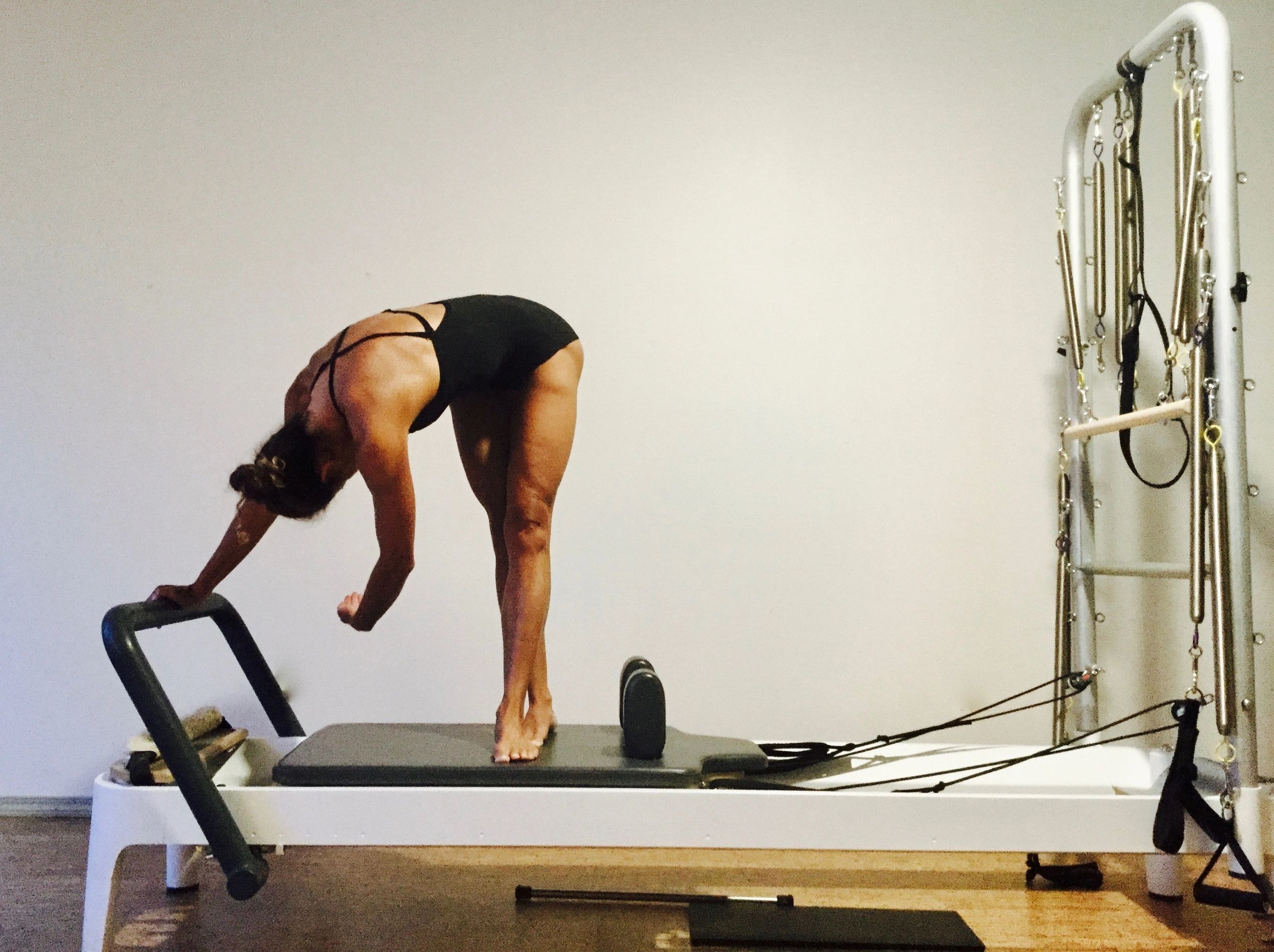 Woman performing forward bend on Pilates reformer